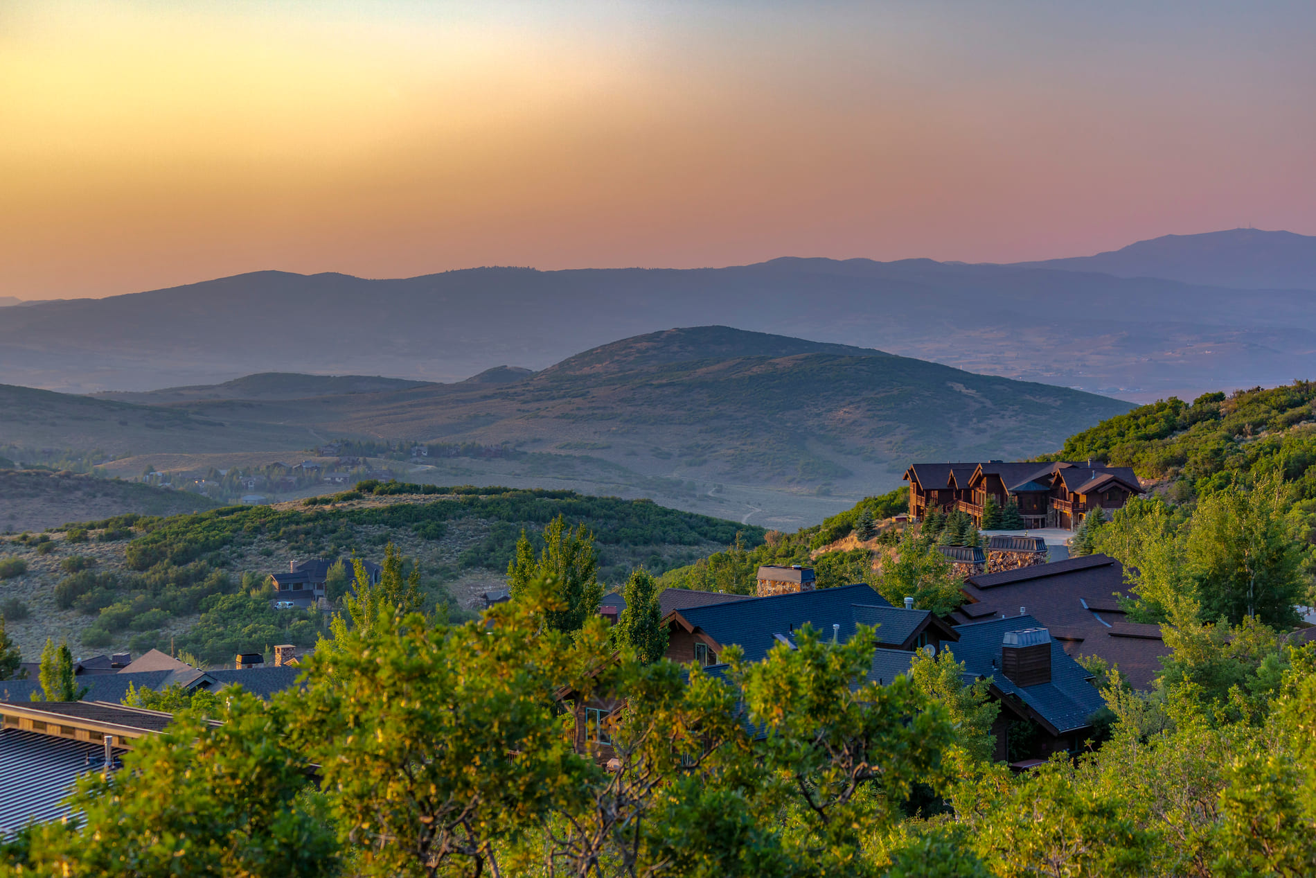 Homes sitting amongst a beautiful sunset with mountains in the background in Park City, Utah.